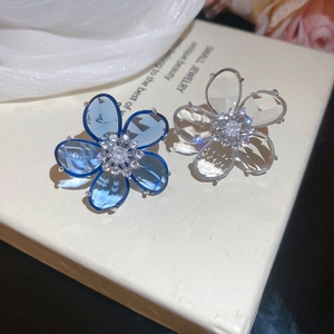 Close-up of blue and white zircon flower ear clips with detailed crystal petals