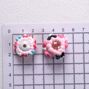 Detail of two pink doughnut-shaped hand-painted acrylic beads for DIY phone chains