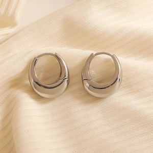 Polished silver chunky teardrop hoop earrings on textured fabric in minimalist style