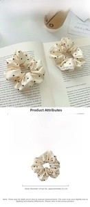 Detailed view of beige satin polka dot hair scrunchies on a book with lace trim and dimensions