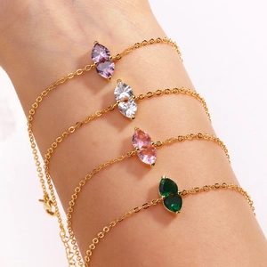 Close-up of heart-shaped birthstone bracelets in gold plating on a woman's wrist