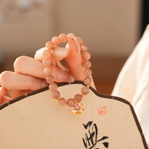 Detail of sunstone beaded bracelet featuring a colorful rocking horse enamel charm