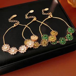 Detailed view of vintage gold flower bracelets with colorful zircon stones on black leather