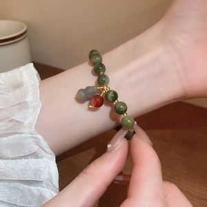 Detail of colorful beaded bracelet with gold charm worn on wrist over a wooden table