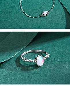 Detail of silver S925 oval moonstone bracelet and ring set on dark green background