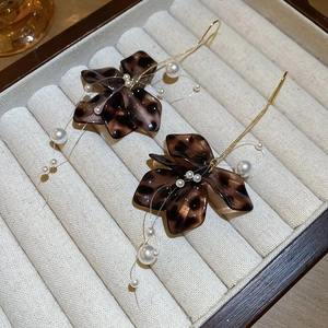 Detail of brown leopard print petal earrings with dangling pearls on a velvet jewelry tray