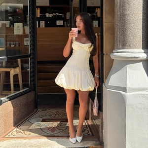 Detail of light yellow mini dress featuring a fitted bodice and flared bubble hemline