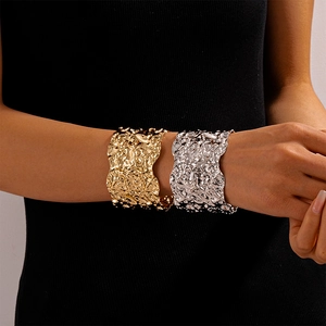 Detail of wide metallic cuff bracelets with irregular hammered texture in gold and silver