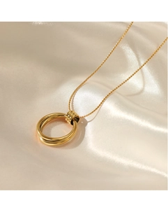 Detailansicht goldener doppelter Ringanhänger auf Satin mit geriffelten Details am Glied