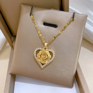 Luxurious gold heart pendant necklace with 3D rose and diamonds on a beige cushion