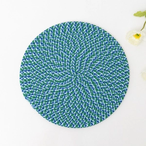 Handwoven round cotton placemat in blue, green, and white spiral pattern for heat resistance