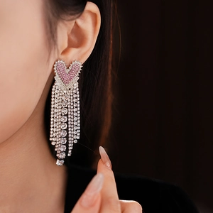 Close-up of pink heart stud earring with sparkling silver tassels worn by model
