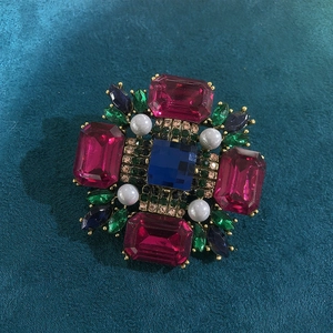 Vintage gold brooch with blue square crystal and multicolor rhinestones on dark fabric
