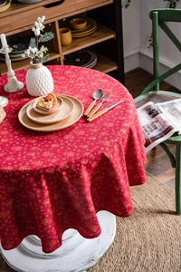 Detailed view of red Christmas tablecloth featuring golden snowflake and bell prints