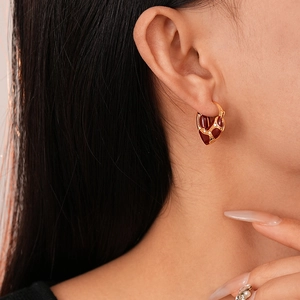 Primo piano di orecchini a cuore in smalto rosso vintage placcati oro con cristalli