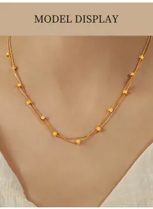 Doellagige goldene Perlenkette als Nahaufnahme am Modell für Styling-Details gezeigt