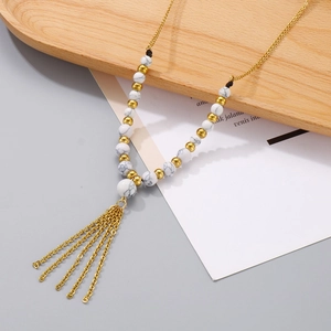 Set collana con frange dorate e perline di marmo bianco su un vassoio di legno chic