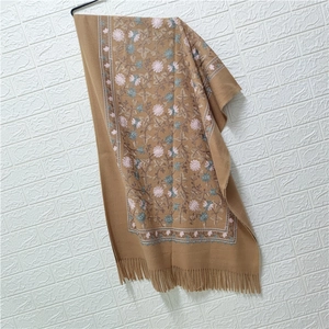 Detailed pink floral embroidery and fringe trim on a camel cashmere-style shawl scarf