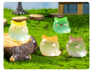 Detailed macro view of four colorful translucent resin kitten figurines in a miniature garden