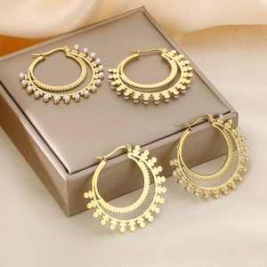 Vintage gold layered hoop earrings with pearls and rhinestones on a silk background