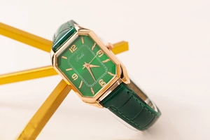 Detail of emerald rectangular dial watch with rose gold case and green leather strap