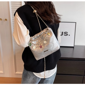 Close-up of quilted silver bucket bag featuring colorful heart charms on a chain strap