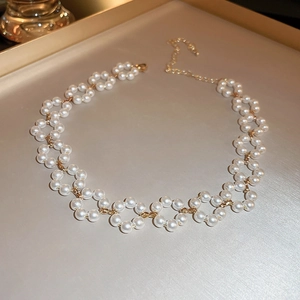 Détail macro du collier ras de cou élégant en perles et fleurs avec chaîne dorée fine