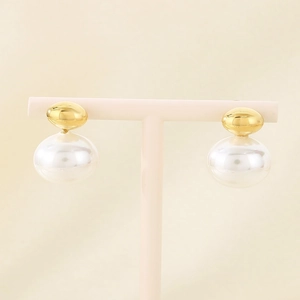 Close-up of elegant gold bow stud earrings with large white pearls on a display stand