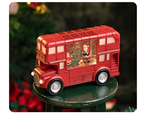 Illuminated red Christmas bus ornament with Santa and snow globe inside on wooden stool