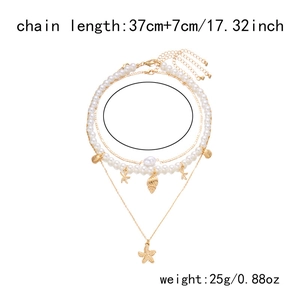 Detail view of multi-layer gold necklace with starfish charms and pearls on white background