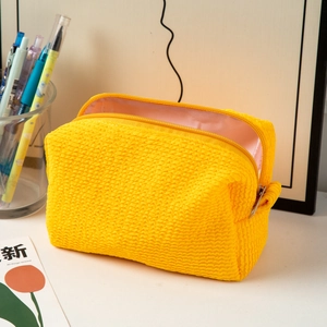 Detail of yellow waffle texture makeup bag with double zippers and soft fabric lining