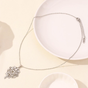 Close-up of silver stainless steel star pendant with vine pattern on a minimal background