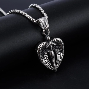 Detailed view of silver heart-shaped angel wings and sword pendant on a black prop