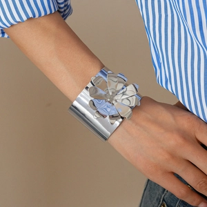 Detail of silver metallic flower cuff bracelet with polished mirror finish on model