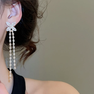 Close-up of sparkling butterfly tassel earrings with cubic zirconia on a model