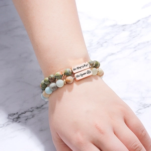 Detail of natural stone bracelets with Her King and His Queen engraved rose gold charms