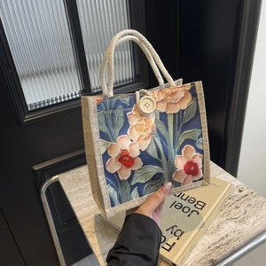 Detail of linen tote bag with colorful floral print, woven rope handle and wood button