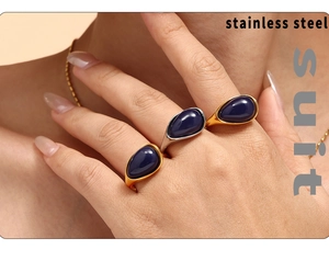 Detail of stacked teardrop rings in gold and silver with deep blue stone inlays
