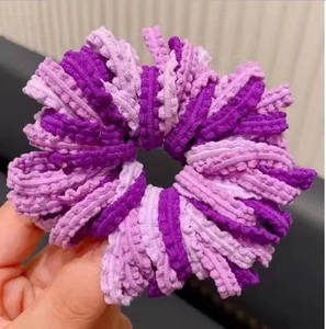 Détail d'un chouchou au crochet à rayures violettes avec un design en maille plissée