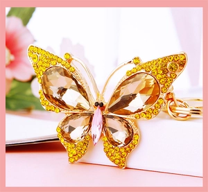 Close-up of golden alloy butterfly keychain with colorful crystals and amber rhinestones
