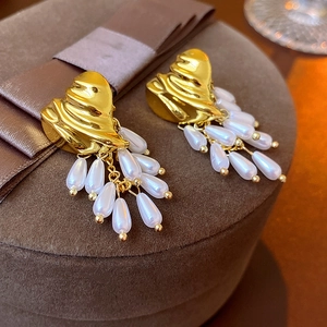 Close-up of vintage gold heart earrings with pearl tassels on a velvet jewelry box