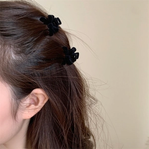 Close-up of a mini black velvet bow hair claw clip worn on side-swept hair