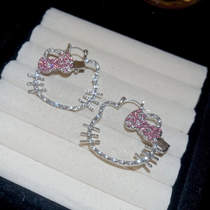 Detail of silver cat-shaped earrings with pink and white rhinestones on a jewelry tray