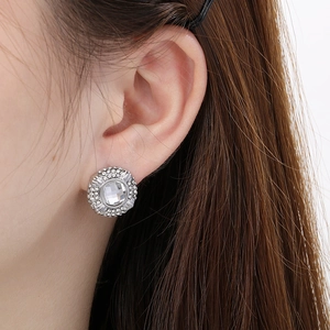 Macro shot of a silver stud earring with a large round diamond and halo of small crystals