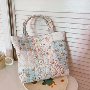 Detail of floral patchwork quilted tote bag with simple wish label on white background