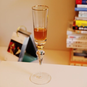 Elegant handmade crystal glass champagne flute with gold rim and bead detail on desk