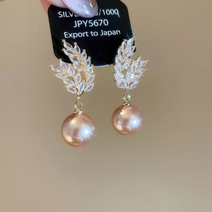 Detail of 925 silver ear studs featuring champagne pearl and zircon wheat leaf motif
