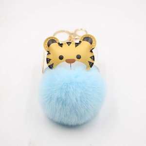 Close-up of blue faux fur ball keychain with cute tiger charm and golden metal clasp