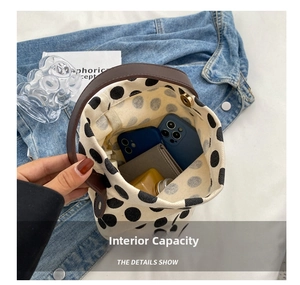 Internal capacity of polka dot canvas bucket bag showing phone, wallet, and cosmetics