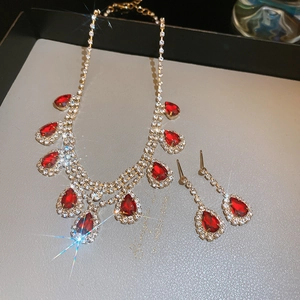 Macro detail of gold necklace and earrings set with red teardrop stones and rhinestones